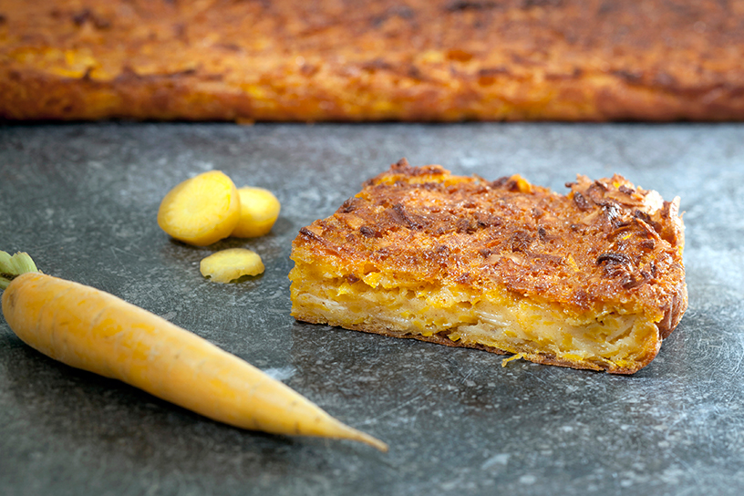 Een stukje geleworteltaart met een wortel ernaast